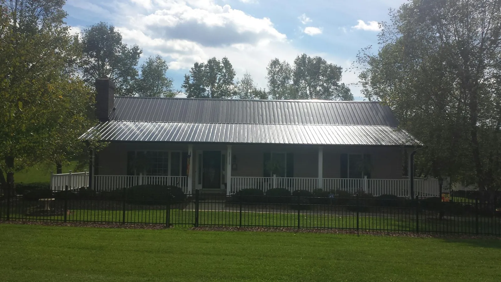 Gray metal roof on a brick ranch with a full width front porch — Gutter Guard Installation work by our crew in Gayville