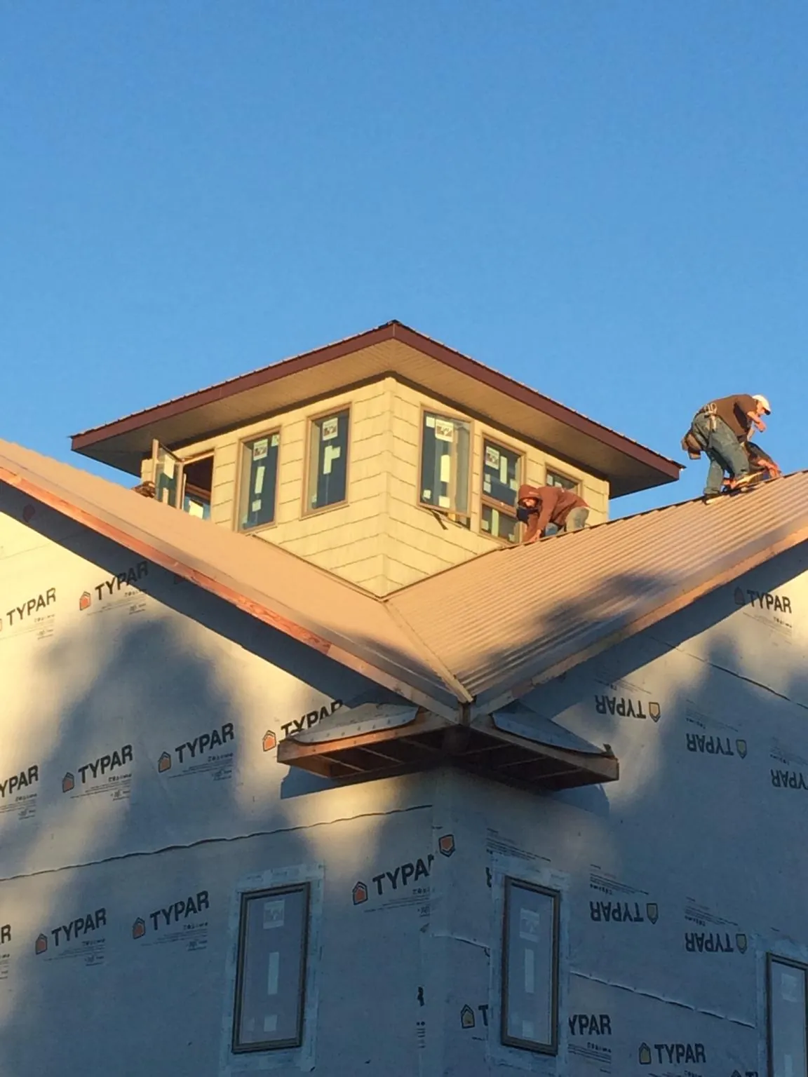 Roofers working around a rooftop cupola on a new metal roof at sunset — Roof Waterproofing in Gayville by Roofing Brothers